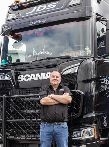 A Portrait photo of Gavin, Advanced Driver stood in front of a Black Scana JBS truck 