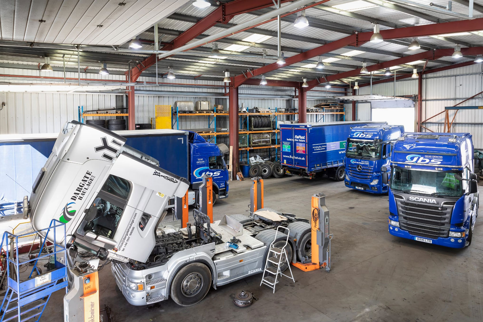 A image inside our expanded workshop, to the left of the image is a white truck being worked one while 2 other trucks are parked up behind it 